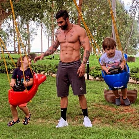 Gusttavo Lima posa sem camisa e mostra tanquinho em parque com os filhos